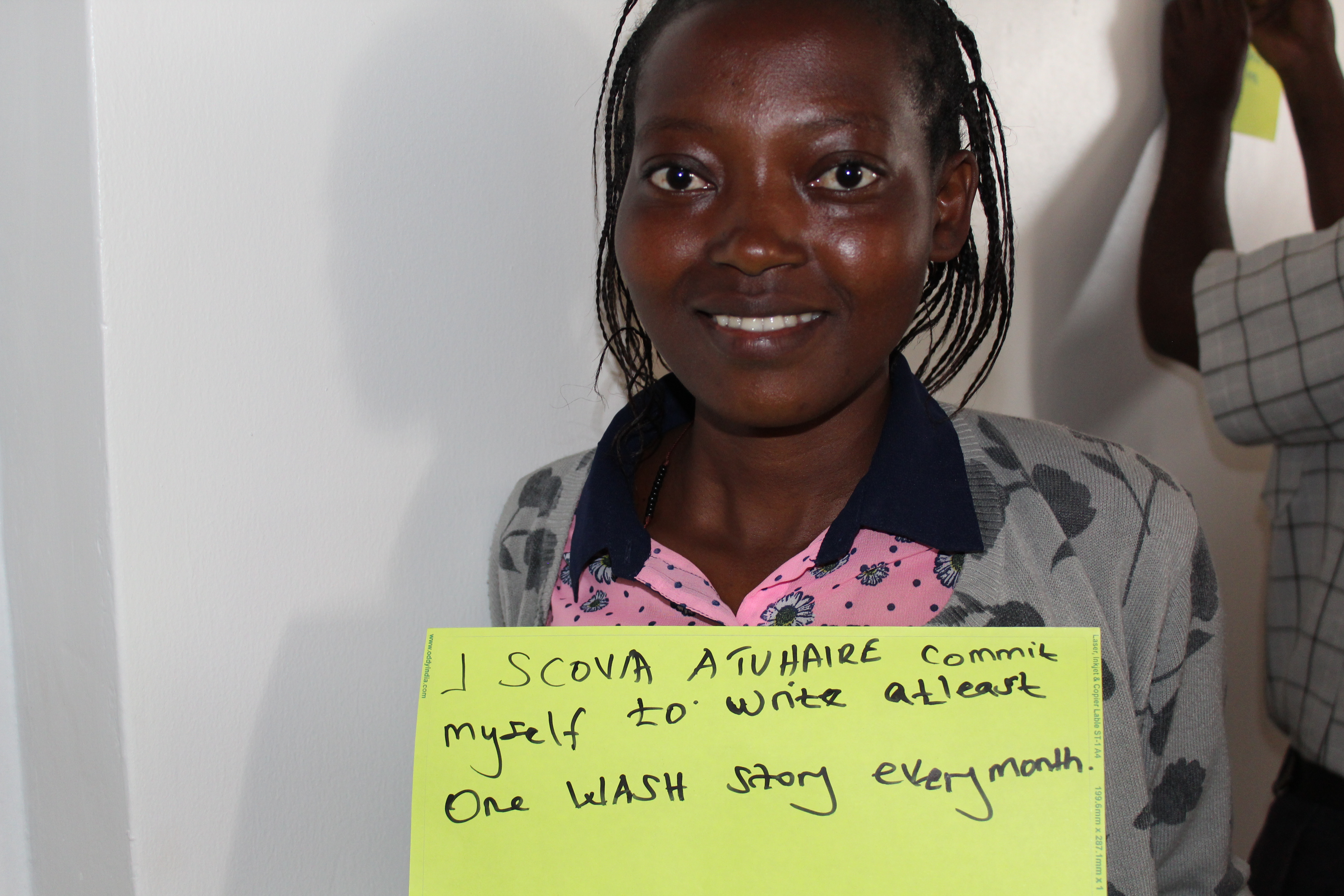 A journalists holds up a placard stating her commitment to WASH coverage