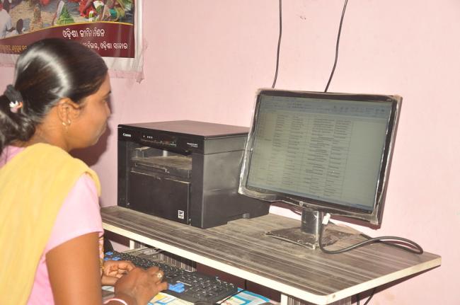 Woman sitting in front of computer screen in Ganjam district, Odisha, India