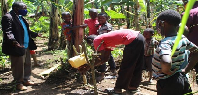 A family demonstrates to the monitoring team how they practise handwashing at home using a tippy tap