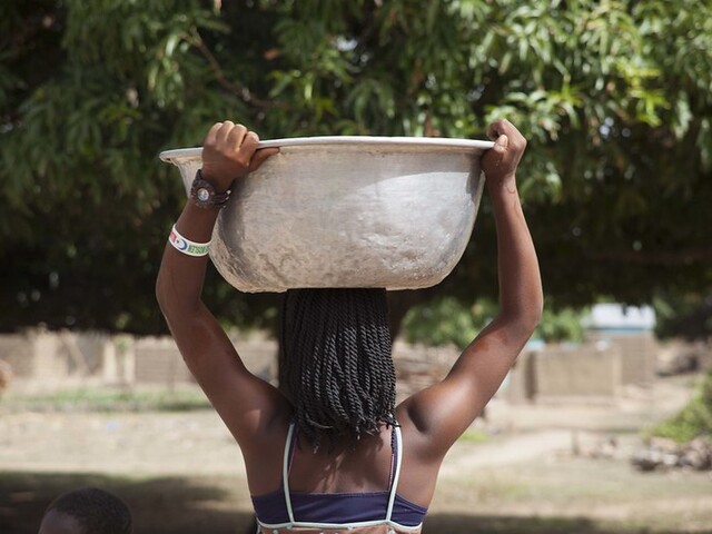 Girl carrying water on her head in Ghana