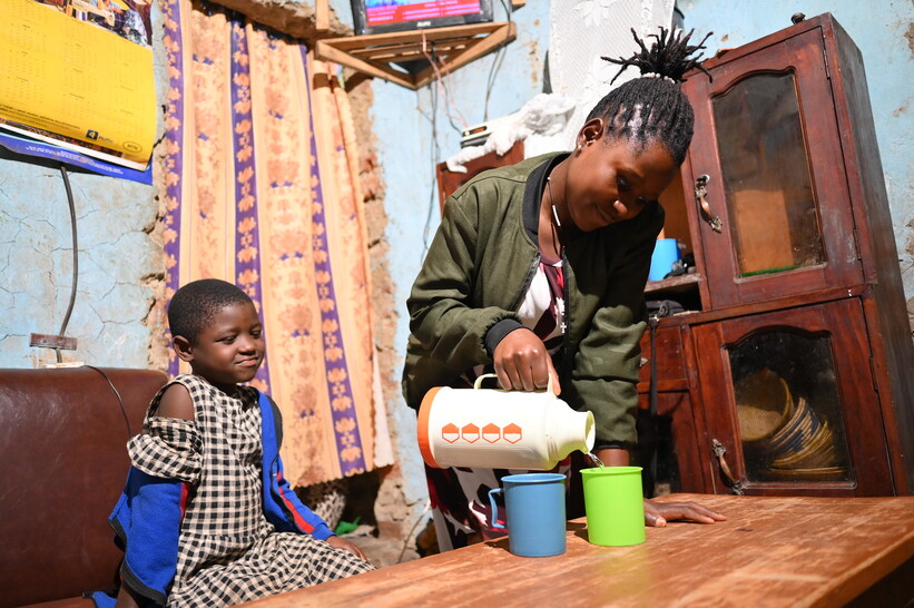 Grace Kansiime and her daughter enjoying safe water from a new household water connection