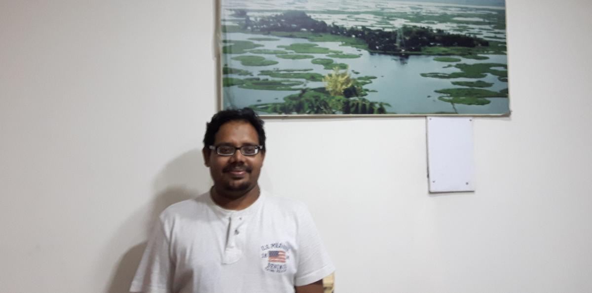 Dr. Ritesh Kumar standing in front of photo of Loktak Lake. Photo: C. Dietvorst/IRC